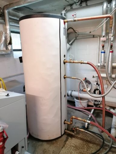 Großer Speicherbehälter mit angeschlossenen Heizungsleitungen und Armaturen in einem Technikraum.