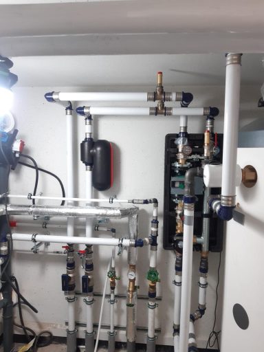 Heizungsinstallation mit Pumpen, Ausdehnungsgefäß, Ventilen und Rohrleitungen in einem Technikraum.