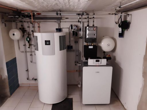 Heizungsanlage mit großem Speicher und Wärmeerzeuger in einem vollständig ausgestatteten Technikraum.