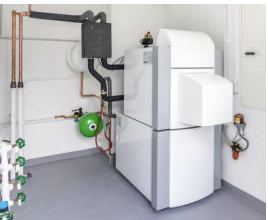 Installierte Wärmepumpen-Inneneinheit mit angeschlossener Heizungs- und Regeltechnik in einem Technikraum.