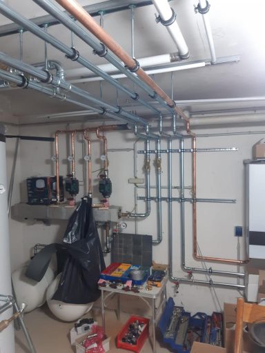 Heizkreisverteilung mit Pumpen, Ventilen und Rohrleitungen in einem Technikraum.