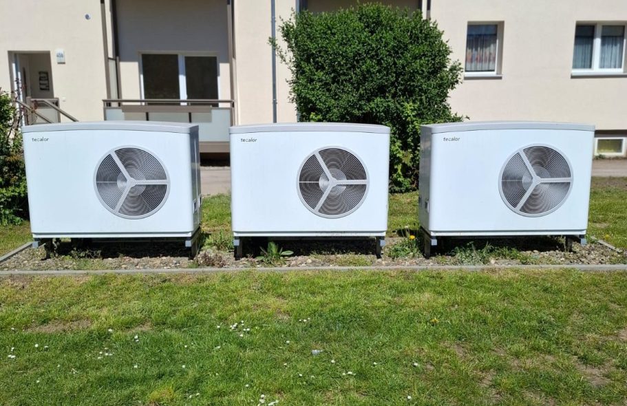 Drei Wärmepumpen im Mehrfamilienhausprojekt Drei installierte Luft-Wasser-Wärmepumpen vor einem Wohngebäude für die zentrale Wärmeversorgung mehrerer Wohneinheiten.