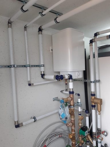 Wandhängende Heizungs- oder Warmwassertechnik mit Rohrleitungen, Pumpen und Armaturen.
