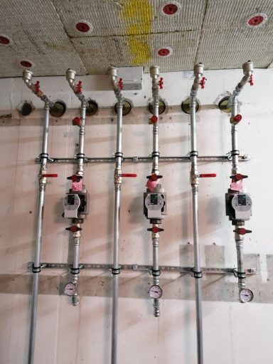 Heizkreisverteilung mit mehreren Umwälzpumpen, Ventilen und Rohrleitungen an einer Wand.