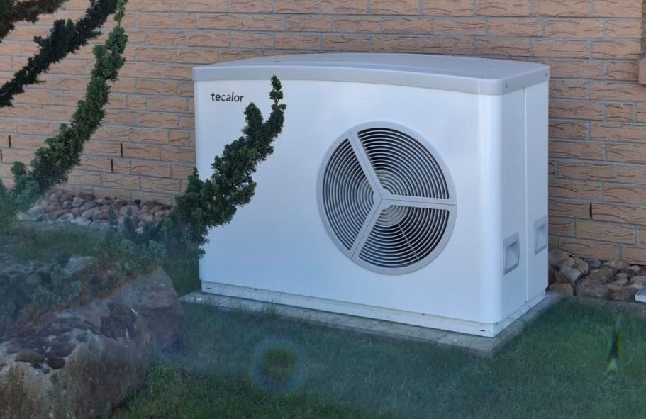Weiße Wärmepumpe am Einfamilienhaus Weiße Luft-Wasser-Wärmepumpe im Außenbereich eines Einfamilienhauses als Beispiel für eine installierte Heizungsanlage.