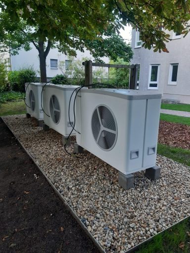 Mehrere installierte Luft-Wasser-Wärmepumpen im Außenbereich eines Wohngebäudes als Referenz für moderne Heiztechnik.