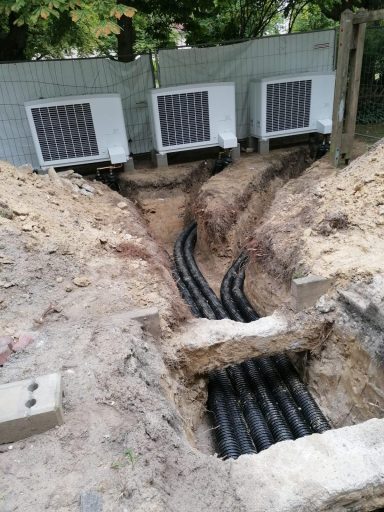 Erdarbeiten mit verlegten Leitungen zu mehreren Wärmepumpen-Außengeräten.