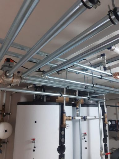 Rohrleitungsinstallation an der Decke eines Technikraums mit mehreren Heizungsleitungen.